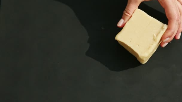 Pohled shora na ženy ruce dát tři kostky bílé marcipánové hmoty na černém stole — Stock video