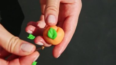 Kadın elinin üst görüntüsü badem ezmesi şekilli şeftali şeklindeki şekere kuru karanfil koyar.