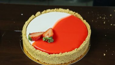 Dilimlenmiş çilekle süslenmiş yuvarlak kırmızı ve beyaz peynirli kek.