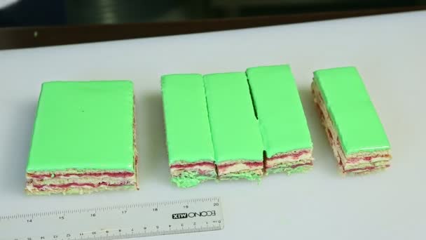 Nahaufnahme von oben viele Portionen grün glasierter Schichtkuchen mit sahniger Fruchtfüllung — Stockvideo