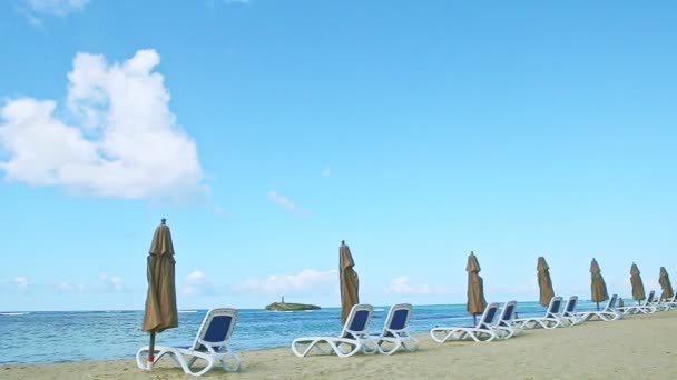 Plaj sandalyeleri ve kapalı şemsiyelerle kumlu okyanus kıyısında yavaş yavaş panorama