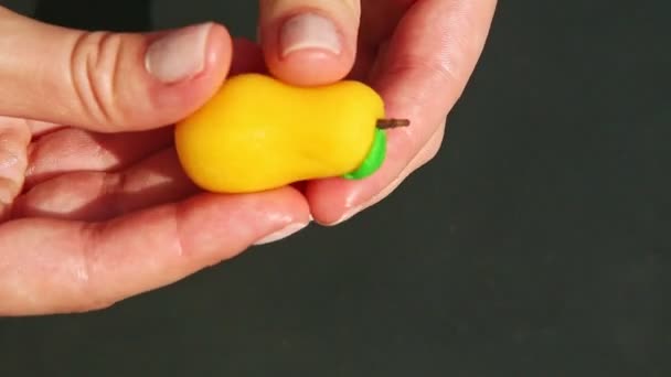 Top view closeup female hand shows and takes away pear shaped marzipan candy — Stock Video