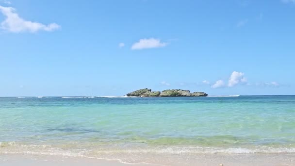 Панорама на маленьких белых волнах от голубого океана до золотистого песчаного пляжа — стоковое видео