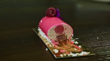 Yakın plan pembe jöleli çikolatalı kremanın yarısı ahududu ile süslenmiş.