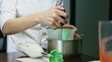 Yakın plan şekerleme büyük plastik kovada ev yapımı yeşil sıvı jöleyi yavaşça karıştırır