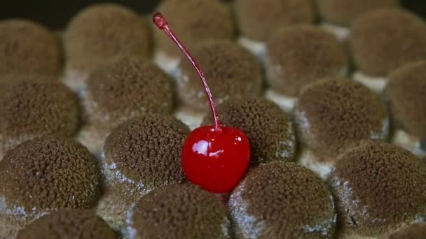 Close-up origineel gevormde chocoladetaart versierd met rode kers draait rond — Stockvideo