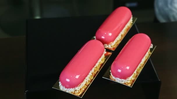 Konfektyr serverar fyra portioner rosa glaserade desserter med kokosnötsspån — Stockvideo