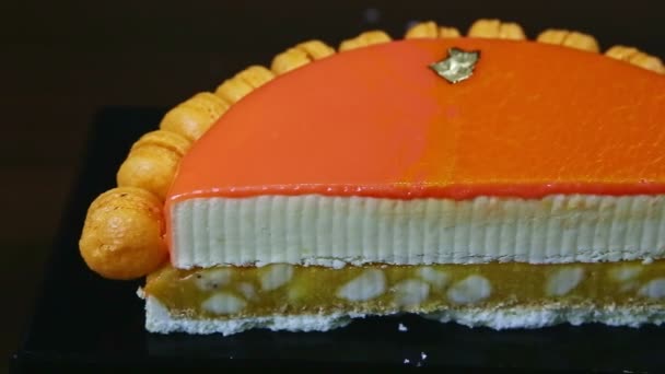 Panorama lent à droite sur la moitié du gâteau au fromage glacé à l'orange sur l'intercalaire amande — Video