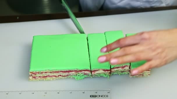 Bovenaanzicht bij vrouw afgesneden door mes op porties groen geglazuurd romig fruit gelaagde taart — Stockvideo