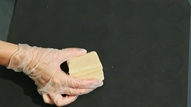 Bovenaanzicht op vrouwelijke handen zet kubus van witte marsepein en giet oranje kleurstof — Stockvideo