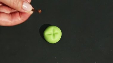 İnsan elinin üst görüntüsü elma şekilli badem ezmesi şekerine kuru karanfil koyar