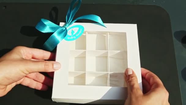 Top view on hand takes off and puts back cover at empty gift box with square sections — Stock Video