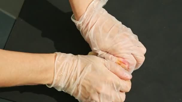 Bovenaanzicht op vrouwenhanden kneed groot stuk witte marsepein met oranje kleurstof — Stockvideo