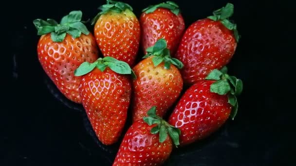 Fokussierung von oben aus einer Gruppe vollreifer roter Erdbeeren auf schwarzer Oberfläche — Stockvideo