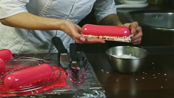 Gros plan confiseur décoration par copeaux de noix de coco rose glaçure gâteau ovale — Video