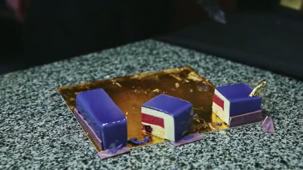 Closeup woman hands take away pieces of violet glazed mousse cake with fruit jelly — Stock Video
