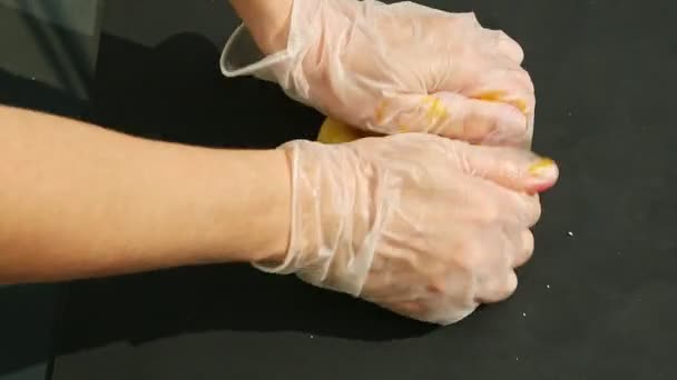 Vista superior primer plano en las manos de la mujer amasar gran pedazo de masa de mazapán amarillo brillante — Vídeo de stock