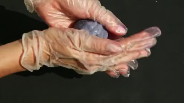 Bovenaanzicht close-up vrouwelijke handen kneden klein stukje violette marsepein massa — Stockvideo