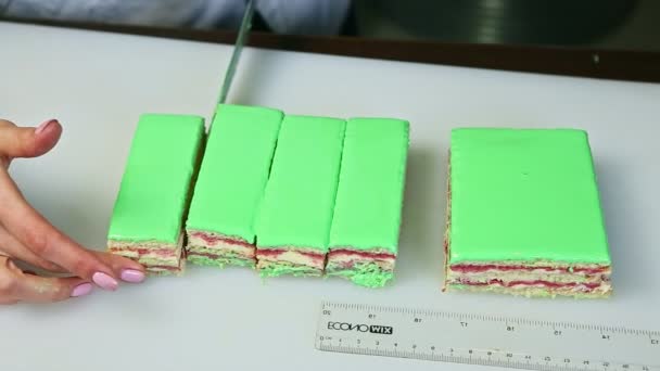 Confectioner cut off by knife on portions green glazed creamy fruit layered cake — Αρχείο Βίντεο