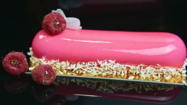 Hindistan cevizi ve ahududu parçacıkları ile süslenmiş pembe jöleli tatlıyı yakından izleyin.