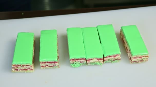 Confectioner hands cut off by knife portions of green glazed fruit creamy layered cake — Stock Video