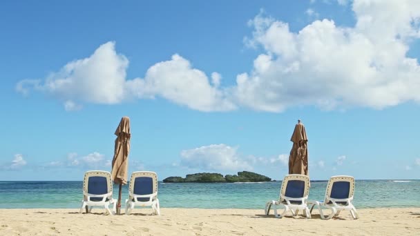 White fluffy clouds fly above empty seashore with beach chairs and closed umbrellas — Stock Video