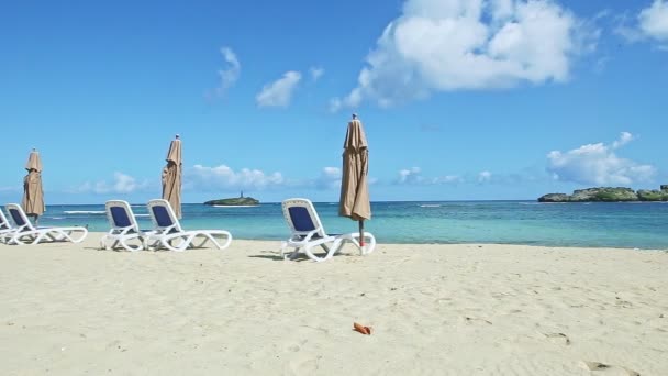 Pomalu panorama na bílém písčitém pobřeží oceánu s plážovými židlemi a zavřenými slunečníky — Stock video