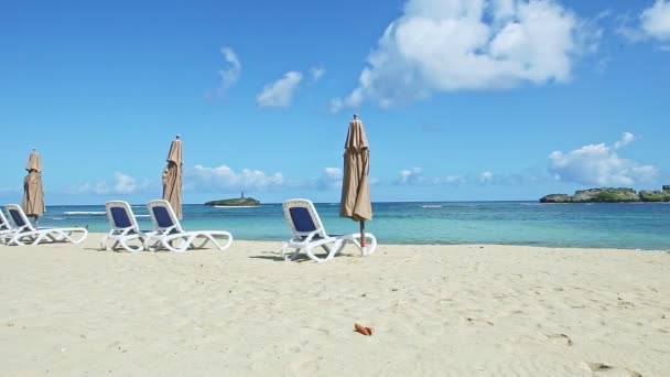 Panorama lento a orillas del mar de arena blanca con sillas de playa y sombrillas cerradas — Vídeo de stock