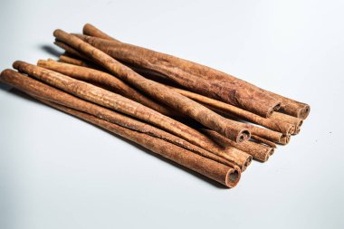 Büyük bir yığın kuru açık kahverengi desenli tarçın çubukları beyaz masa yüzeyinde servis edilir.