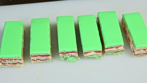Close-up panorama op porties van groen geglazuurde gelaagde taart met fruit romige vulling — Stockvideo