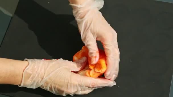 Вид сверху на женские руки в перчатках месить большой кусок апельсиновой массы марципана — стоковое видео