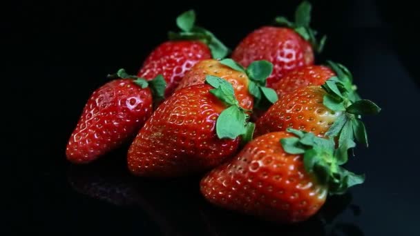 Primer plano grupo de fresas rojas jugosas frescas maduras enteras servidas sobre fondo negro — Vídeos de Stock