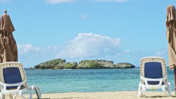 Збільшити з порожнього піщаного узбережжя з довгими пляжними стільцями і закритими парасольками — стокове відео