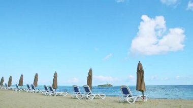 Plaj sandalyeleri ve kapalı şemsiyelerle boş altın okyanus kıyısında panoramik manzara