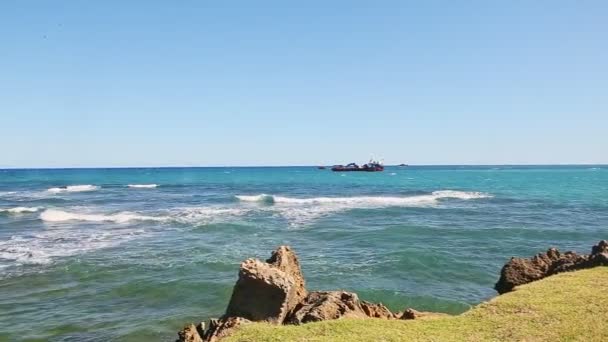 Panorama från stora svarta fartyg till vita vågor i blå hav bryter på stenig strand — Stockvideo