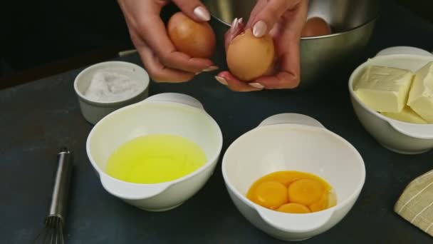 Руки крупным планом женщины разбивают два сырых яйца отделяют желток от белка — стоковое видео