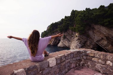 Genç kadın oturur ve deniz ve dağlar bakar