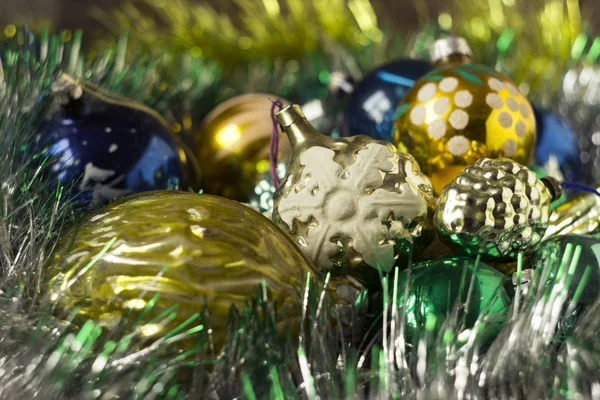 Les jouets jaunes, verts et bleus du Nouvel An reposent sur une guirlande brillante. Vieux jouets en forme de noix, avec l'image de flocons de neige, boules. Nouvel an et fond de Noël, concept — Photo