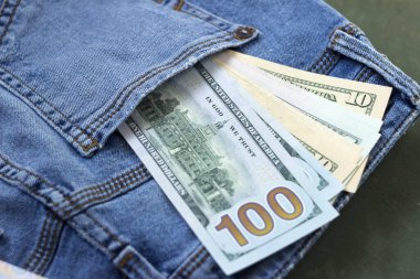Kadın kotunun cebinde farklı mezheplerin banknotları, arka plan. Kavram, Amerikan doları.