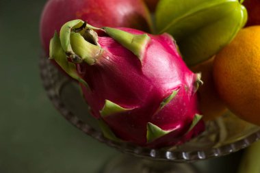 Cam vazoda bir sürü tropikal meyve var. Egzotik meyveler: averrhoa carambola, Pitahaya, Mango, Plantain, mandalina, nar meyvesi. yeşil arkaplan
