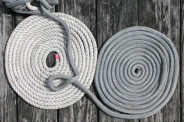 Une corde de bateau en nylon blanc et une corde grise sur le pont en bois — Photo