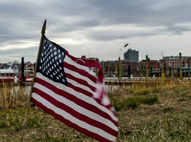 NORWALK, CT, ABD - 10 Mart 2020: Kasaba silueti olan ziyaretçi limanı yakınlarındaki rüzgarda Amerikan bayrağı