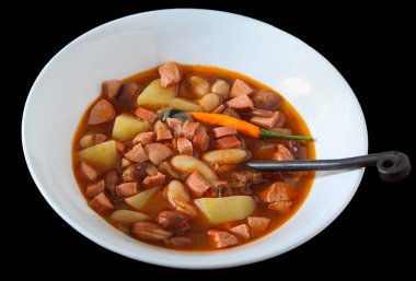 Sosisli fasulye çorbası ve siyah arka planda patates.