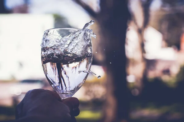 Hand Hält Glas Mit Wasserspritzer Freien Mit Defokussiertem Hintergrund — Stockfoto