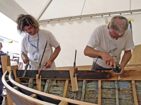 Brest, France - July 14, 2008: Croatian traditional shipbuilders are working on the restoration of an old wooden boat during the maritime festival — Stock Photo, Image