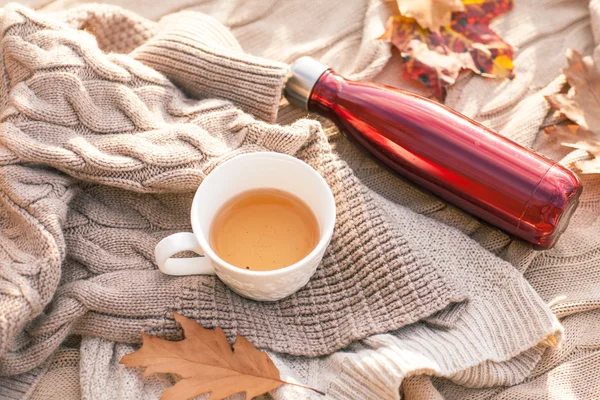 Teplý pletený svetr, šálek horkého čaje a červené termosky — Stock fotografie