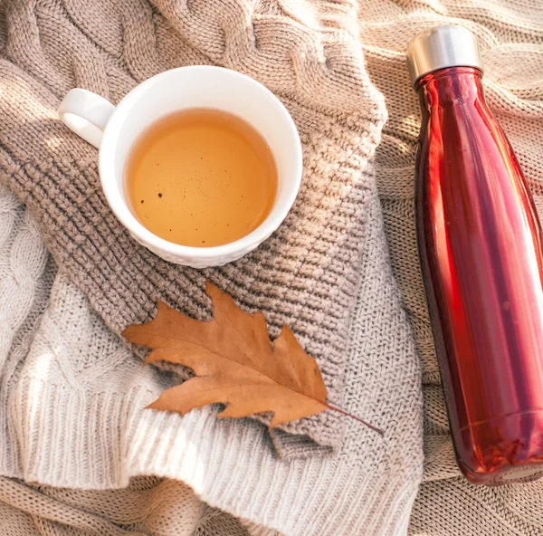 Warm knitted sweater,cup of hot tea and red thermos — Stock Photo, Image