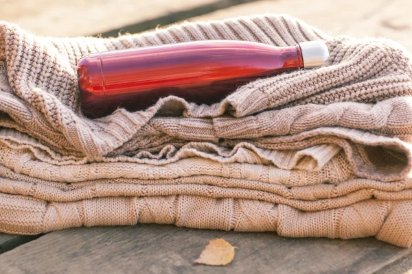 Teplý pletený svetr, šálek horkého čaje a červené termosky — Stock fotografie