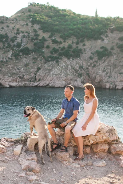Пара парней, играющих со своей собакой на горе возле океана — стоковое фото