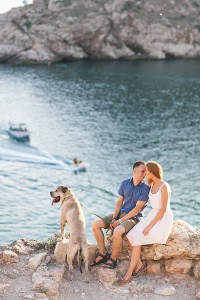 Pár chlapů hrát s jejich psem na hoře nedaleko oceánu — Stock fotografie